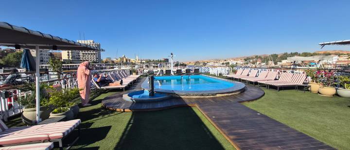 Sun deck of a Nile cruise ship with a pool and loungers overlooking Aswan