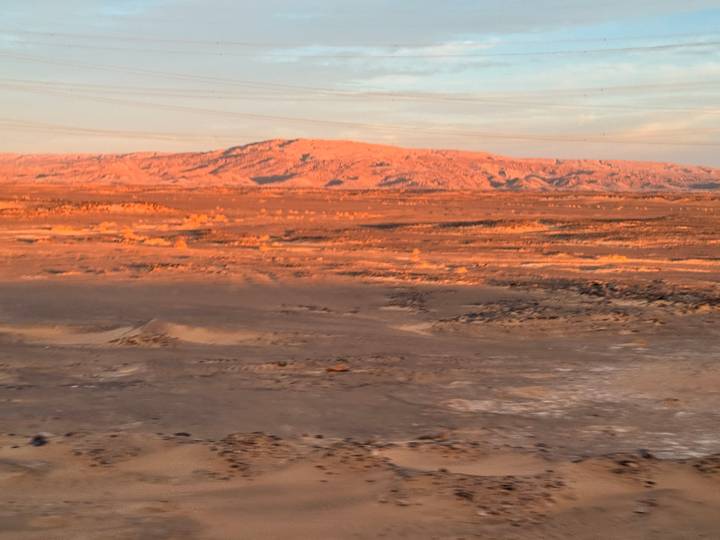 Slightly blurred desert landscape at dusk with soft orange light on distant hills.