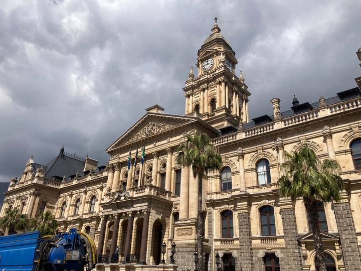 Impressive historic sandstone city hall building under dramatic cloudy skies