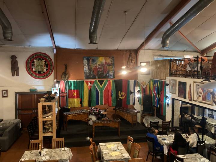 Lively restaurant interior decorated with musical instruments and many national flags of Africa