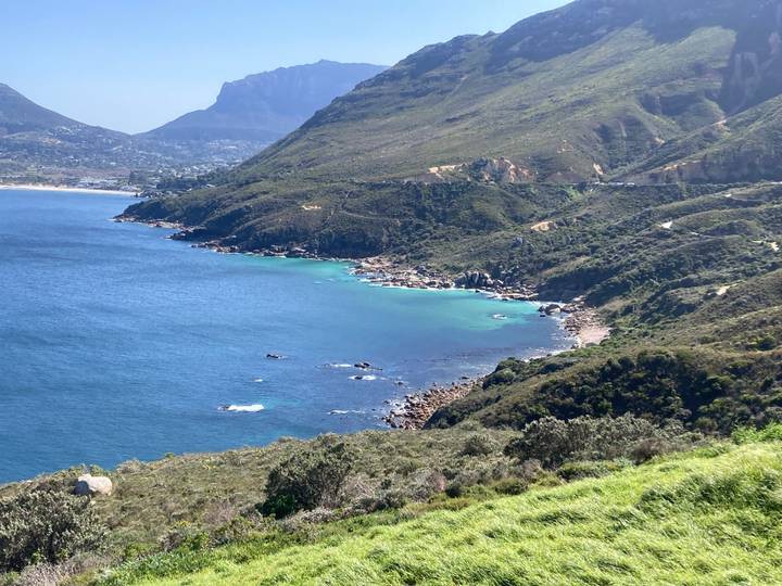 Turquoise waters of Hout Bay framed by rugged green mountains on a clear day