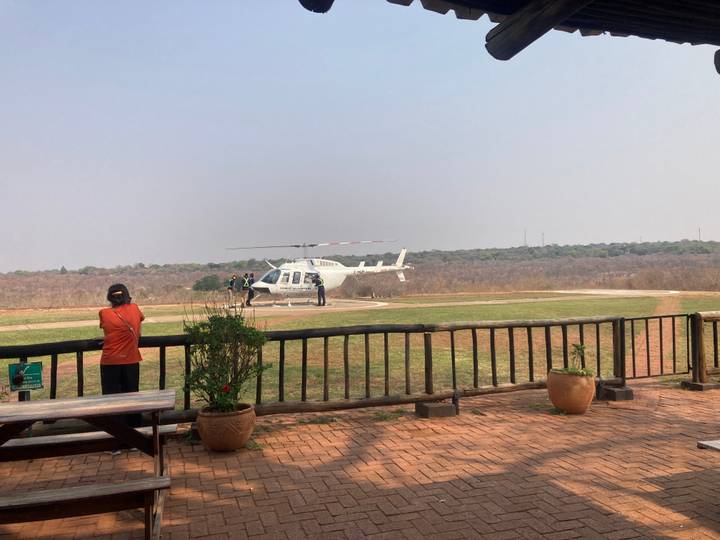 Tourist waiting near a white helicopter on a helipad overlooking dry bushland
