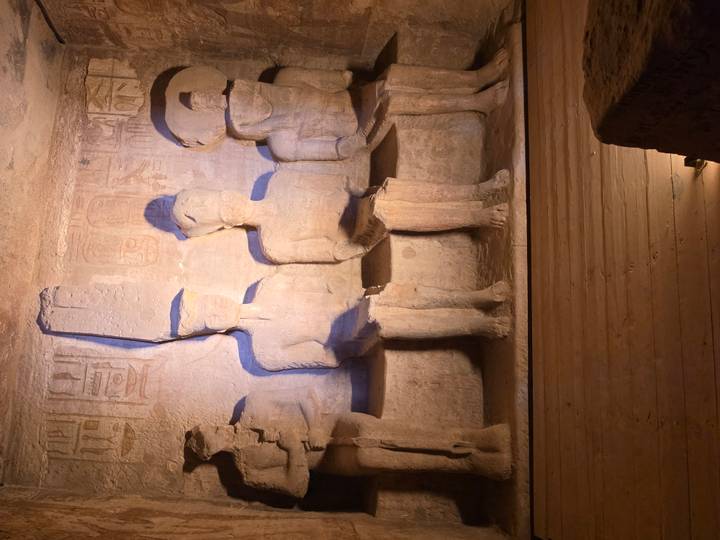 Interior chamber of Abu Simbel showing seated stone gods illuminated by soft lighting.