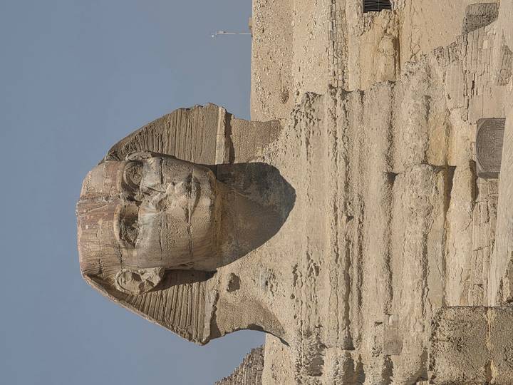 Close-up of the weathered face of the Sphinx under a clear sky.