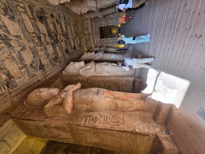 Interior hall of Abu Simbel with towering standing statues and tourists taking photos.