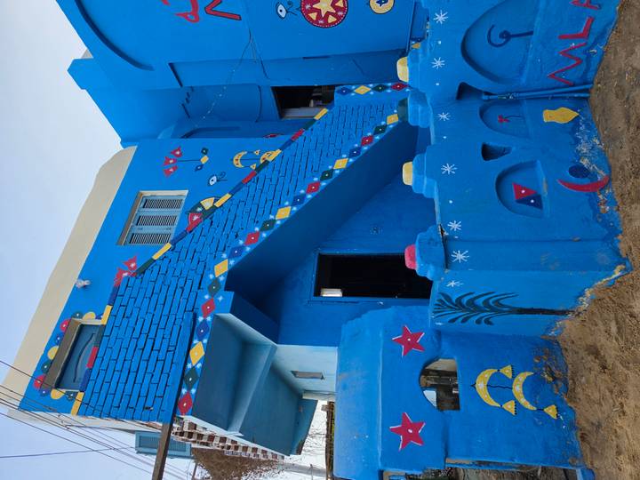 Brightly painted blue Nubian house with decorative motifs and staircase.