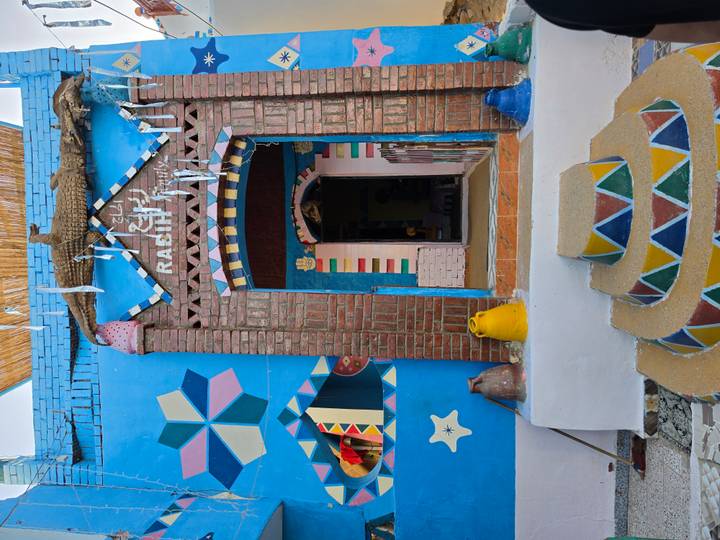 Entrance of a Nubian house with vivid patterns, brick arch and pottery decor.