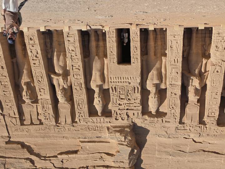 Facade of Abu Simbel small temple with detailed carvings and a visitor at the entrance.