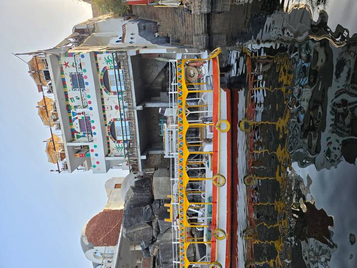 Colorful multi-story riverside building with patterns overlooking a small boat on the Nile.