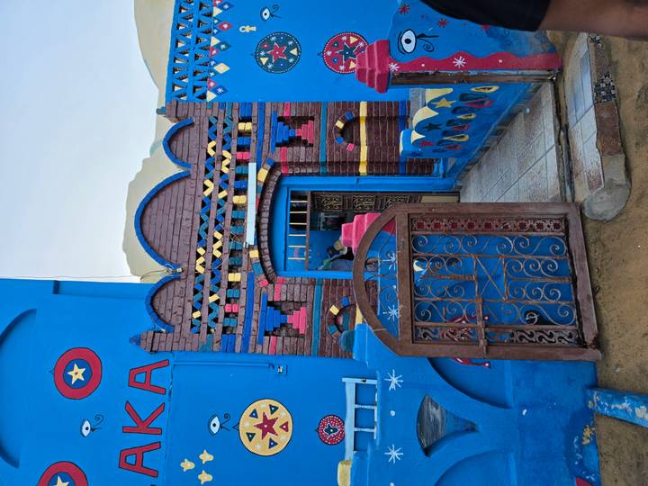 Blue Nubian house front with patterned brickwork and iron gate.