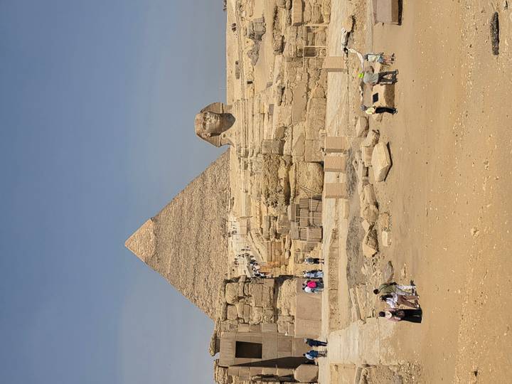 Iconic view of the Great Pyramid of Giza with the Sphinx in front and tourists exploring the site.