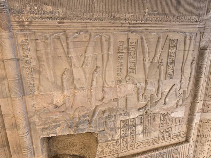Detailed wall relief featuring Egyptian gods and hieroglyphs carved into sandstone temple walls.