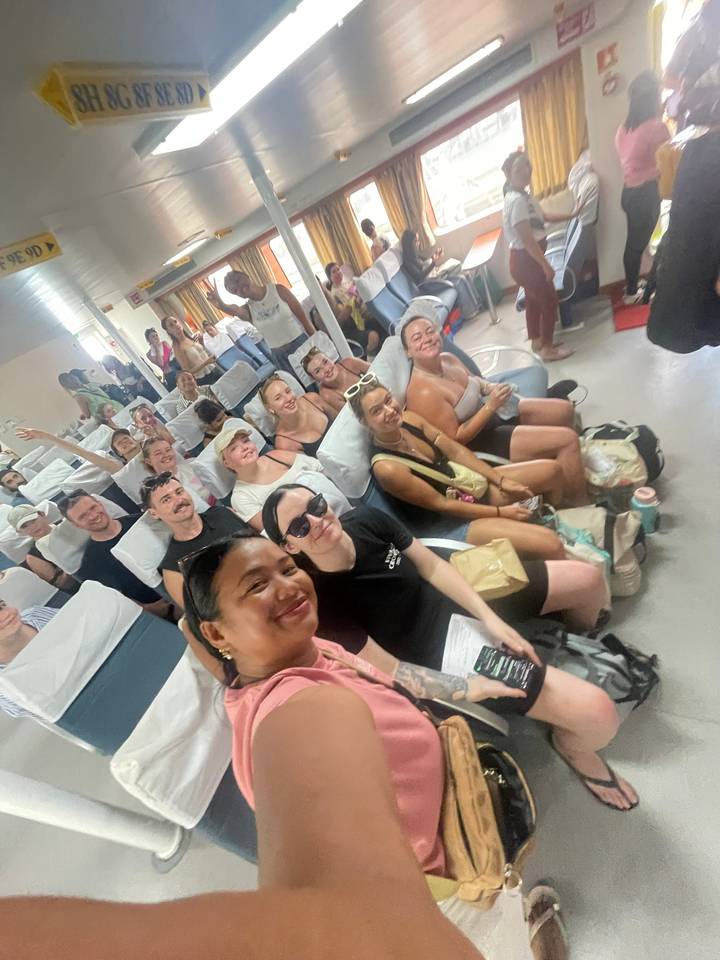 Cheerful tour group takes a selfie inside a crowded ferry cabin.