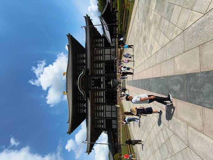 Front view of the grand wooden Todai-ji temple under a blue sky with tourists walking across the broad stone courtyard.