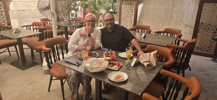 Smiling couple seated at an outdoor restaurant table with Egyptian dishes and drinks