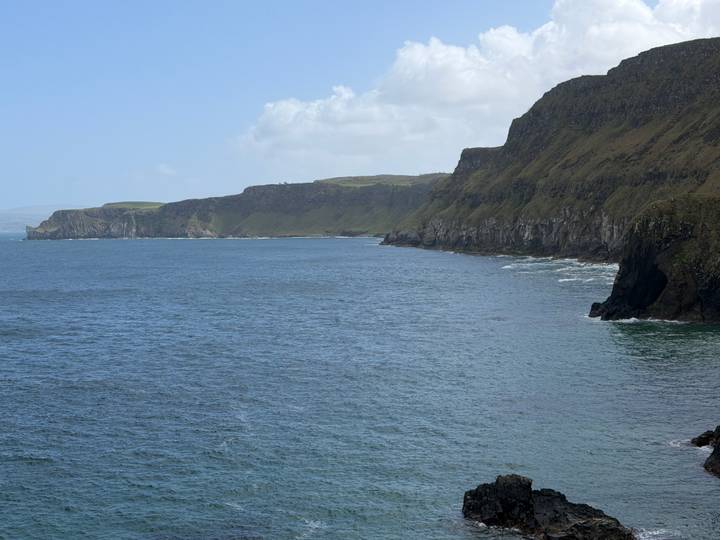Long Atlantic coastline with sheer green cliffs meeting deep blue water under a bright sky