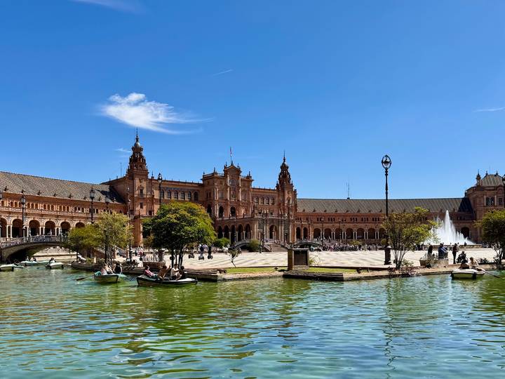 Plaza de España in Seville with rowboats on the canal and ornate towers under blue sky