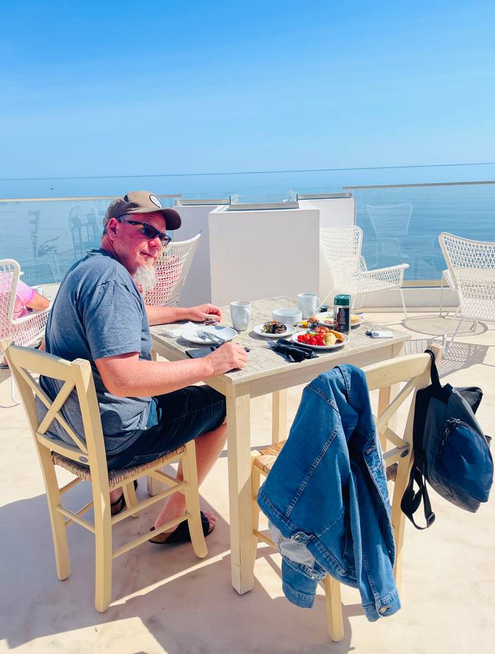 Traveler enjoying al fresco breakfast on a rooftop terrace overlooking the sea