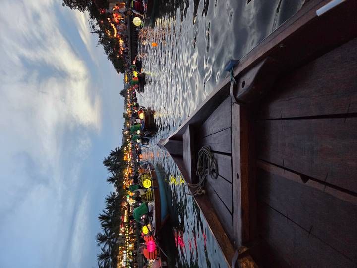 Evening boat ride in lantern-lit waterways of Hoi An with palm silhouettes under twilight sky.