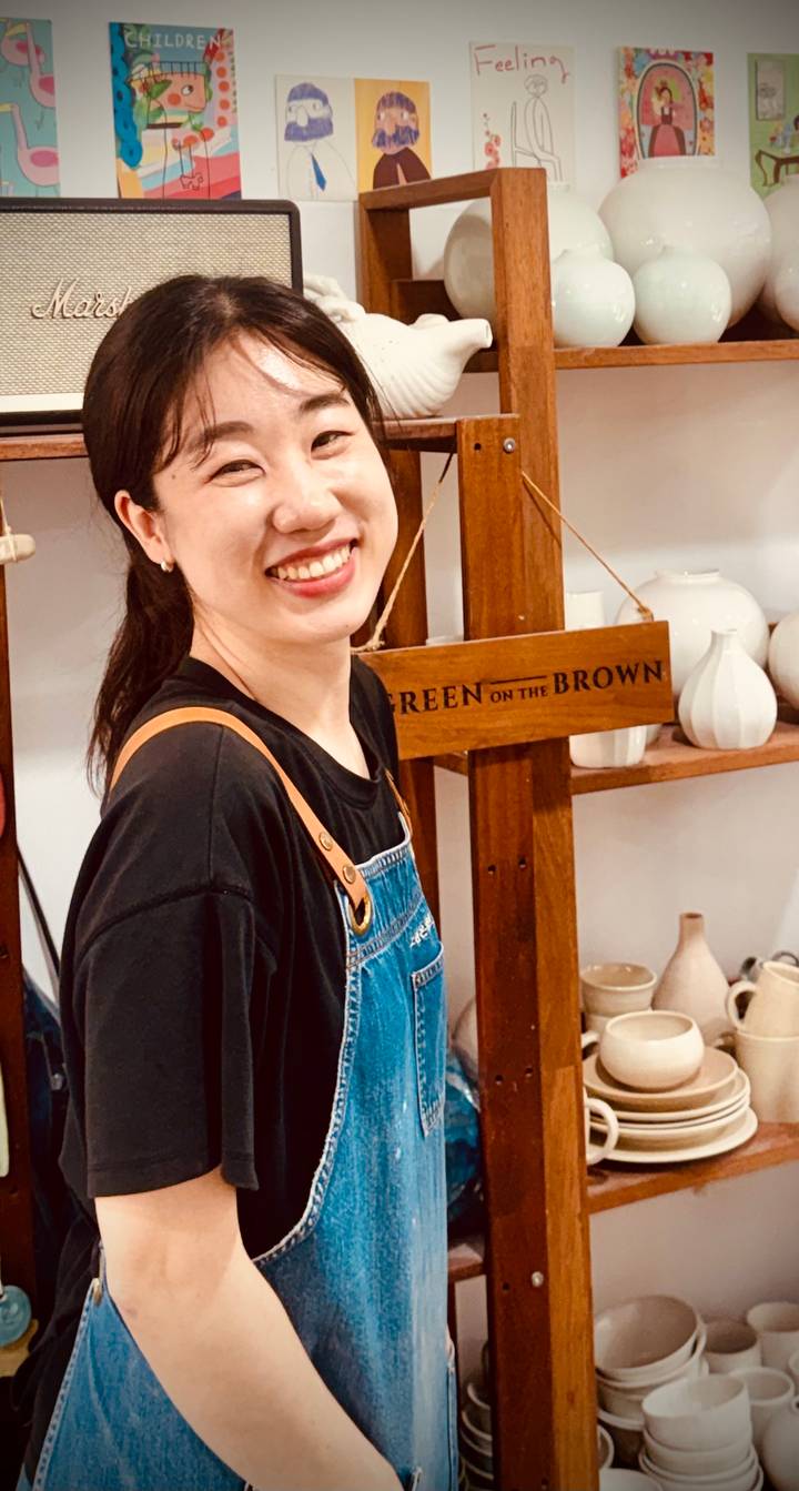 Close-up portrait of smiling woman wearing denim apron indoors