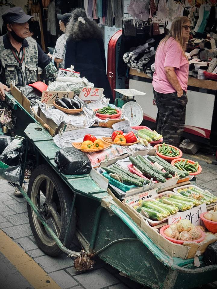 Street cart piled with colourful fresh vegetables and handwritten Korean signs