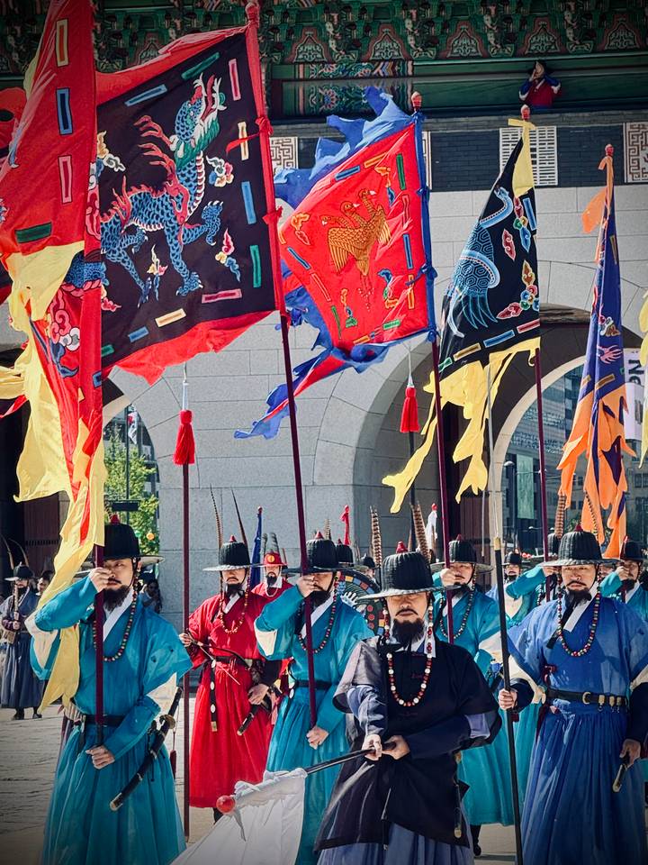 Traditional guards in bright costumes holding vivid flags during royal palace ceremony