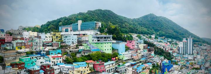 Colourful hillside houses of Gamcheon Culture Village backed by green mountains under hazy sky