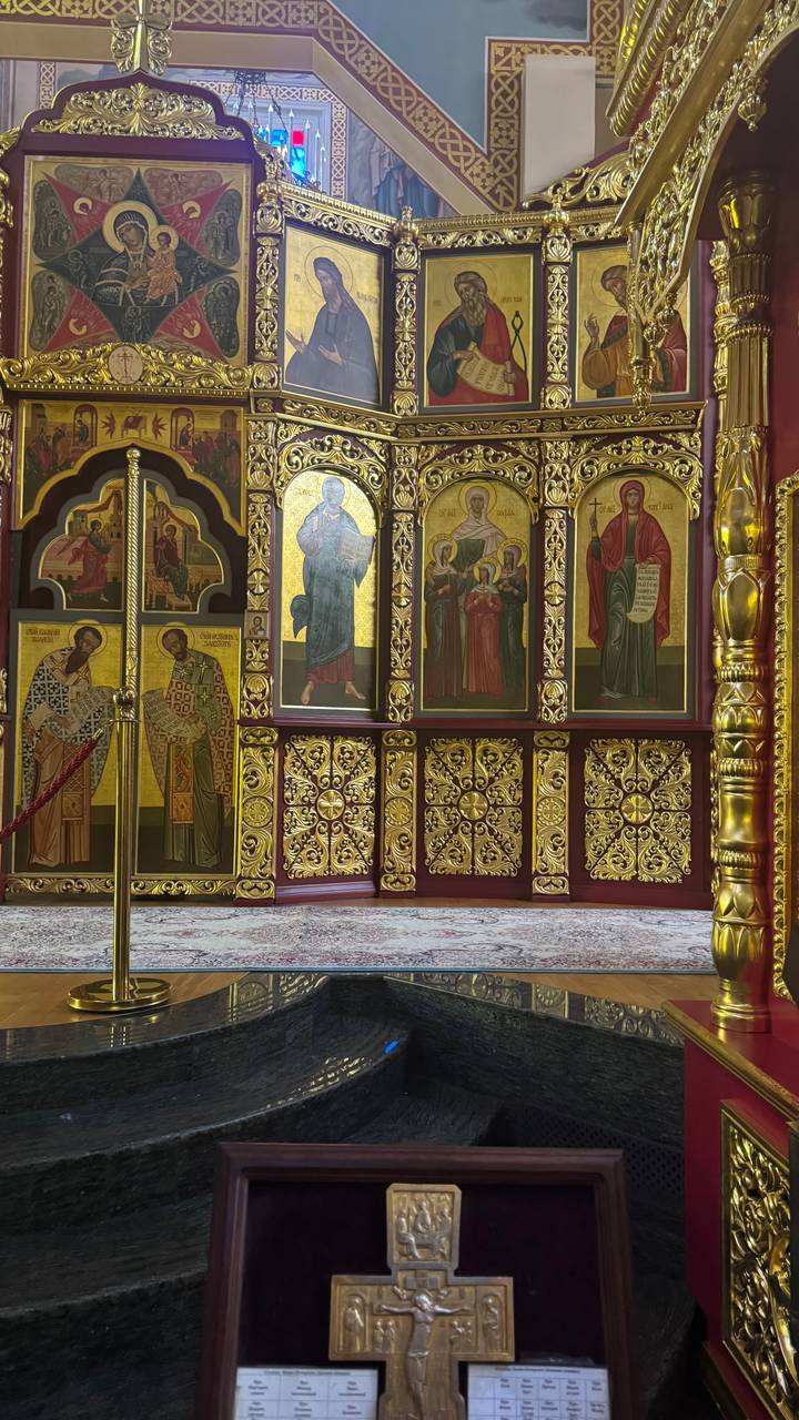 Golden iconostasis panels adorned with detailed religious paintings inside a cathedral.