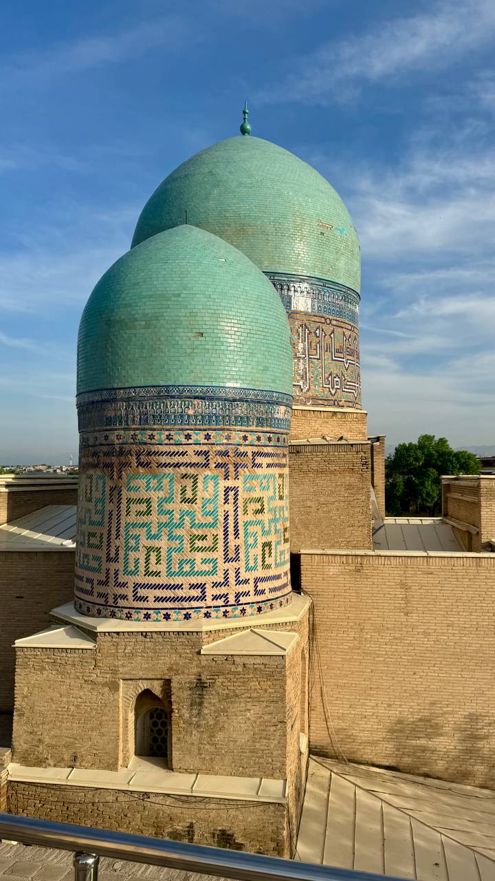 Close view of turquoise-tiled minaret cylinders decorated with intricate geometric mosaics.
