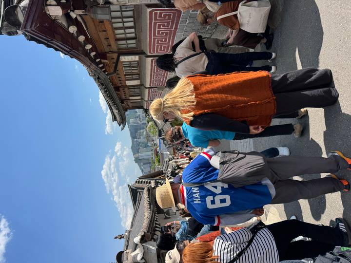 Busy traditional neighborhood street lined with hanok houses crowded with tourists on a sunny day.