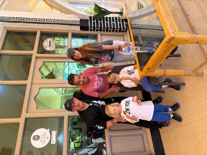 Two adults, a guide and two small children smiling together inside a café entrance