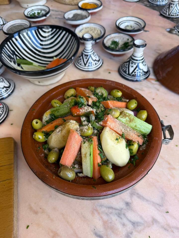 Colourful vegetable tagine with olives and herbs ready for cooking in a clay dish.