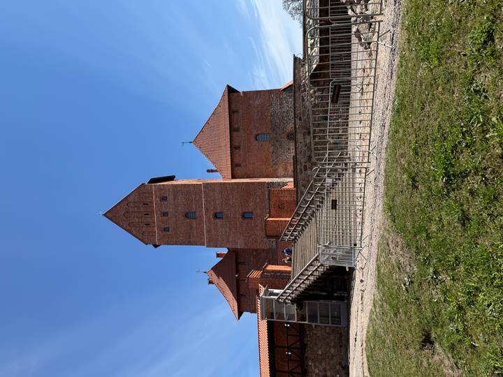Brick tower and walls of Trakai Island Castle under clear spring sky.