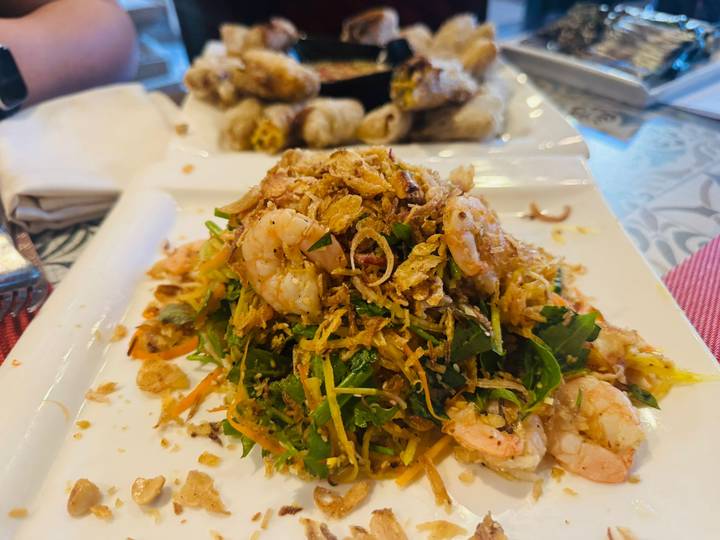 Vietnamese shrimp and herb salad garnished with crispy shallots on a white plate.