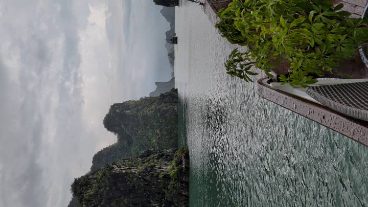 Limestone karsts rise from tranquil green waters of Ha Long Bay viewed from boat deck.