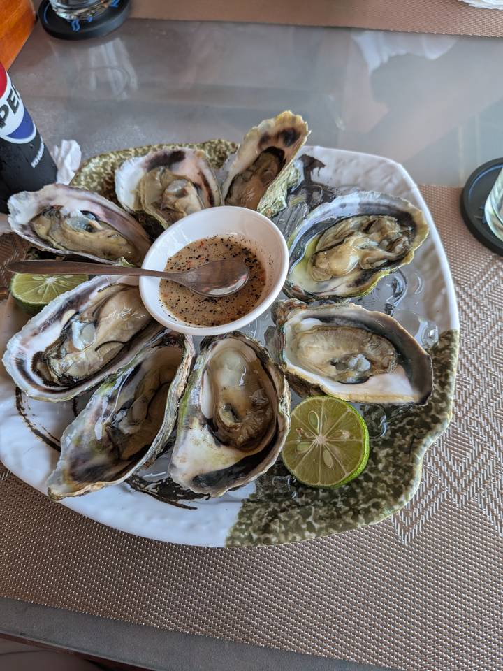 Fresh oysters on ice served with lime halves and pepper dipping sauce.