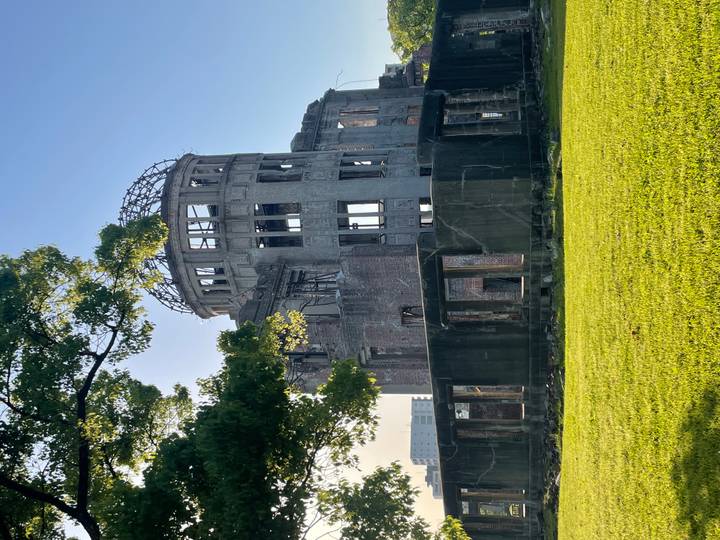 Morning sun lights the ruined Atomic Bomb Dome framed by green lawn and trees