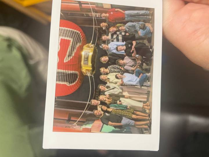 Hand-held snapshot of a printed group photo in front of a large red lantern, slightly out of focus