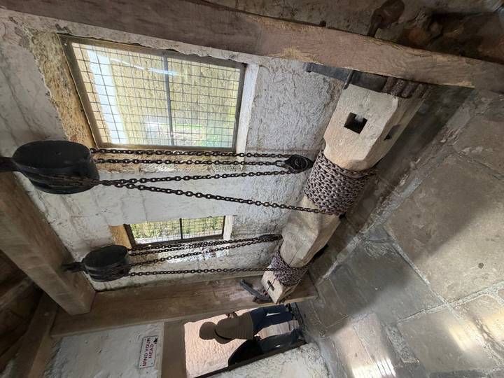 Medieval castle interior with heavy chain and pulley bench device on stone floor.