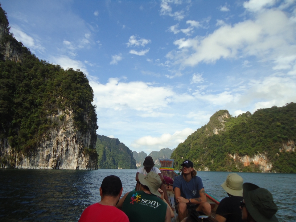 People on a boat exploring a scenic lake with forested cliffs.