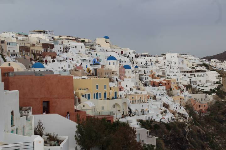 Iconic hillside of whitewashed houses and blue-domed churches cascades toward the sea in Santorini.
