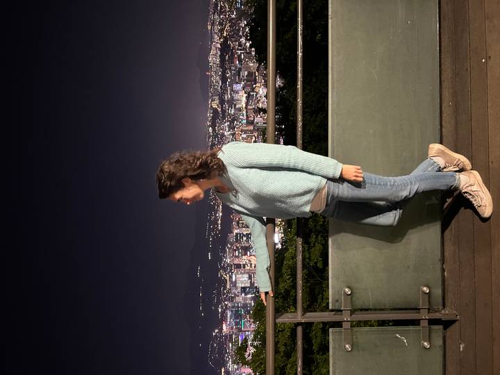 Woman on an observation deck at night overlooking a sparkling city skyline.
