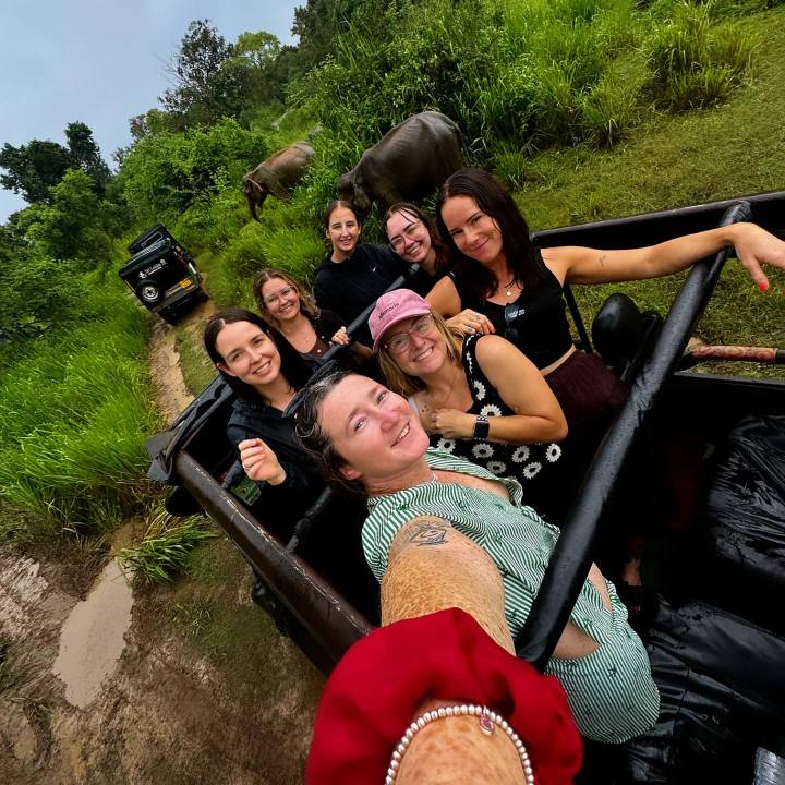 A joyful group selfie on an open jeep during a muddy jungle safari.