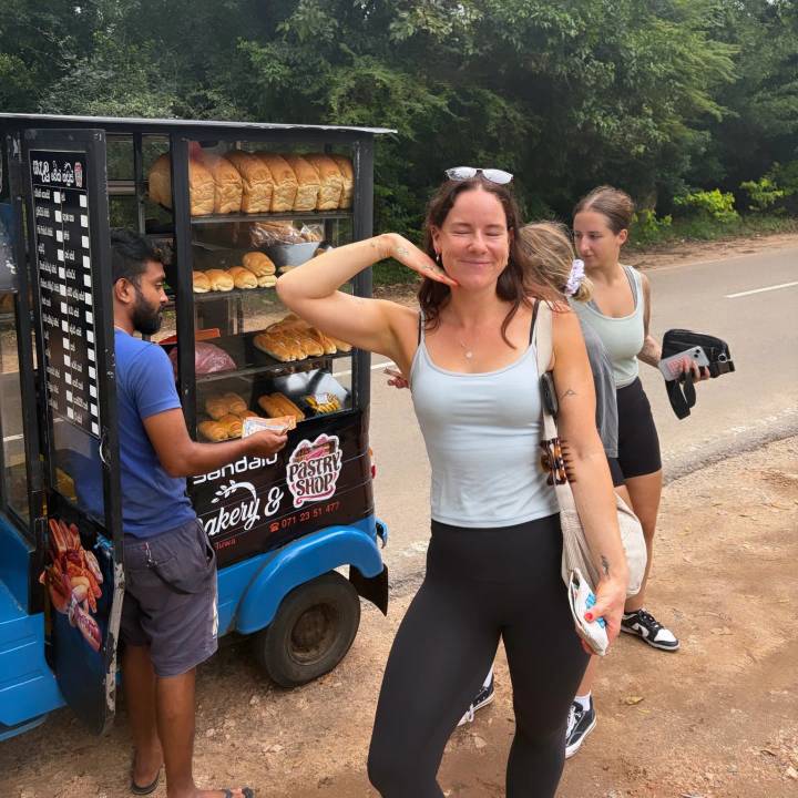 Travellers buy pastries from a colourful roadside tuk-tuk bakery stall.