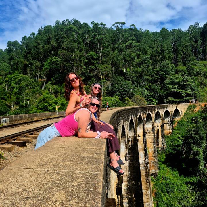 Friends pose atop the famed Nine Arches Bridge surrounded by dense jungle.