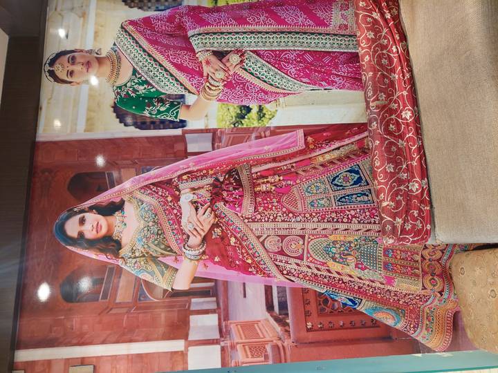 Large poster displaying two women wearing richly embroidered traditional saris