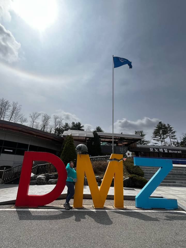 Visitor stands beneath large colourful DMZ letters outside a Korean demilitarised zone attraction