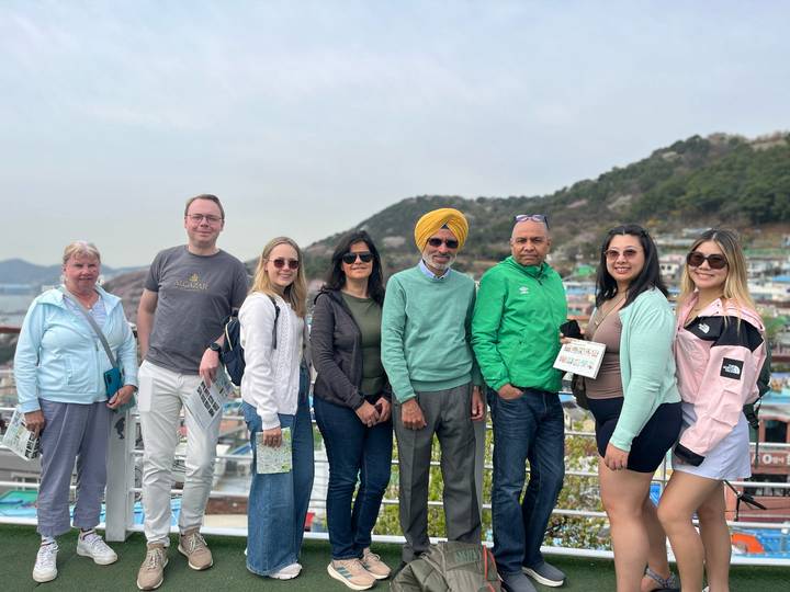 Group of travellers poses in front of hillside Gamcheon Culture Village’s pastel houses