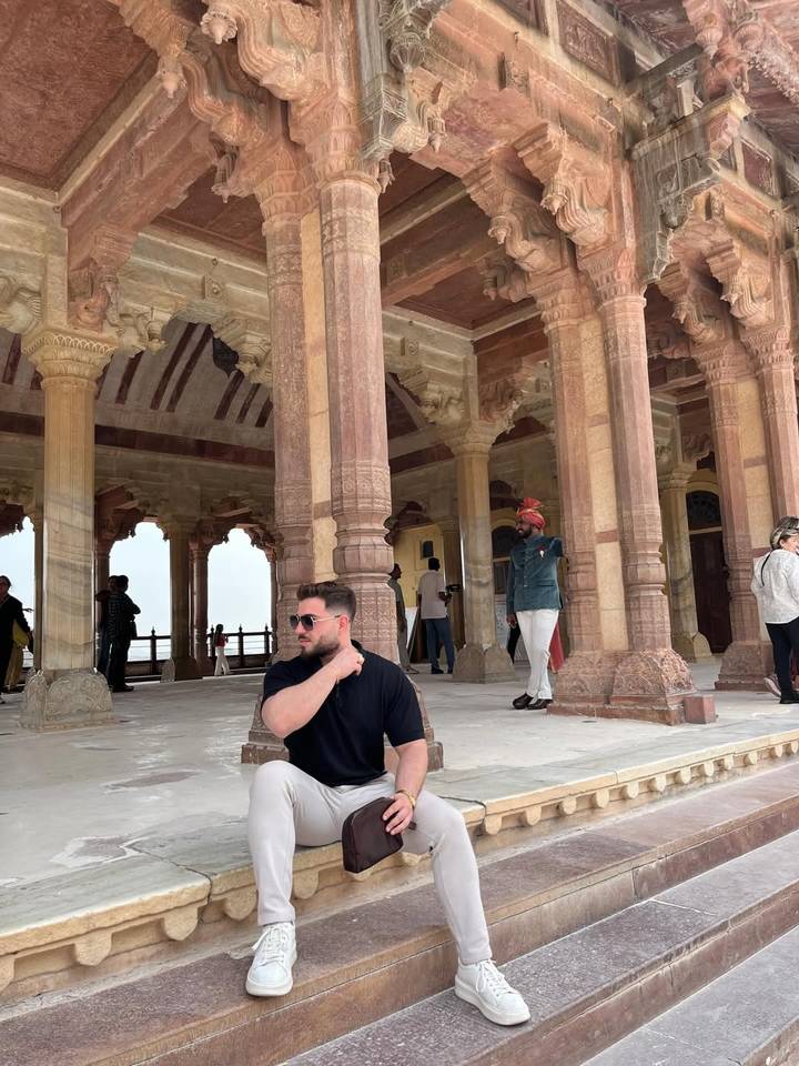 Travellers explore the intricately carved sandstone columns and arches of Fatehpur Sikri palace complex.