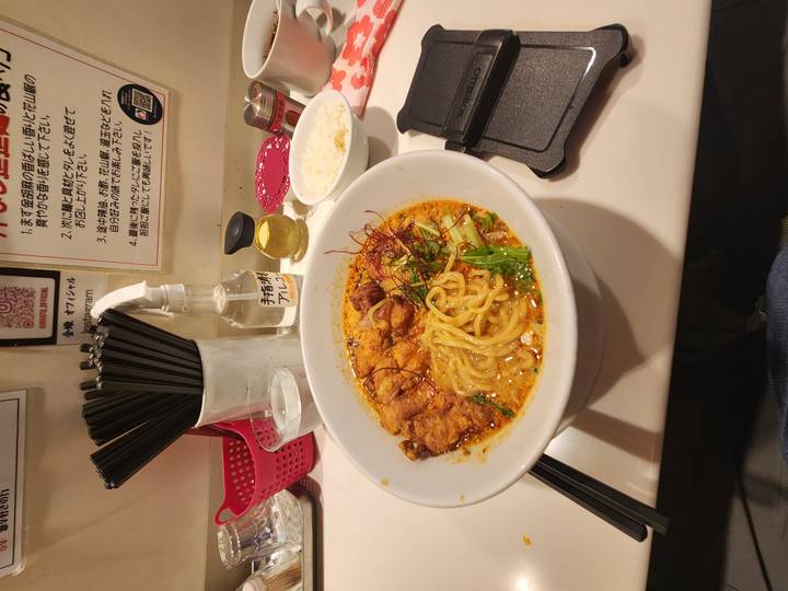 Hearty bowl of spicy ramen with pork and noodles on a counter in a Japanese eatery